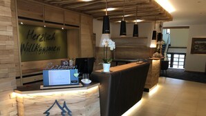 A reception area with a wooden reception desk, a sign reading "Herzlich Willkommen," and a modern interior design with pendant lighting. - Hotel-Gasthof Thüringer Hof (Floh)