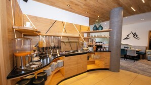 A modern cafe with a wooden counter, shelves with glassware, and a seating area with tables and chairs. - Hotel-Gasthof Thüringer Hof (Floh)