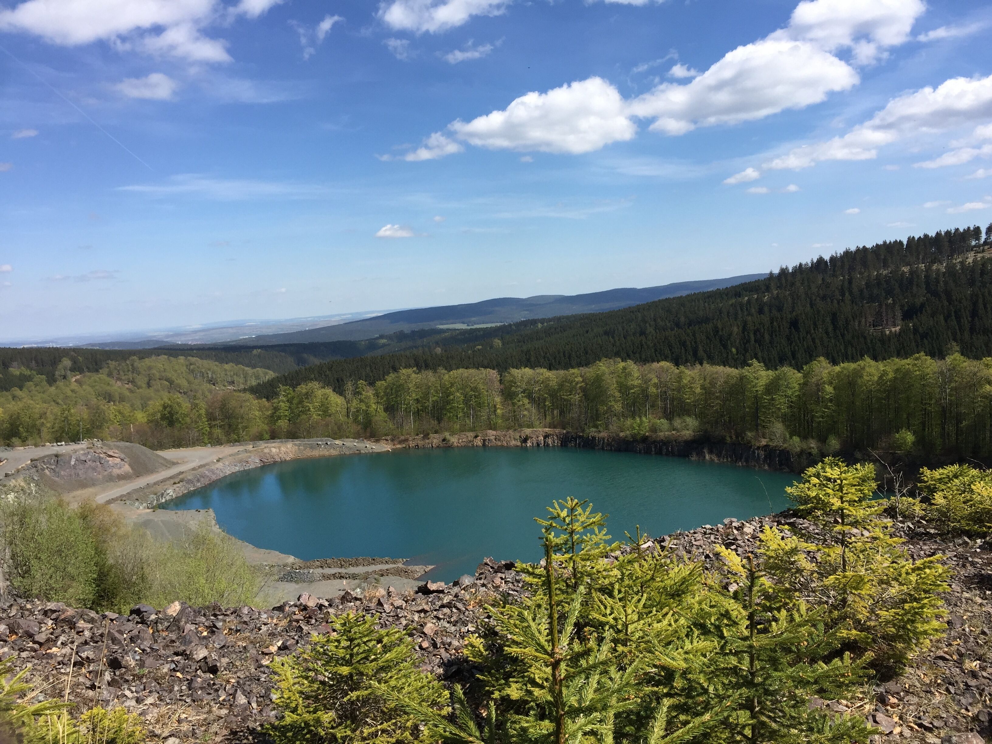 Un paisaje natural con un lago, colinas boscosas y terreno rocoso.