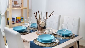 Ein Esszimmertisch ist mit blauen Tellern, klaren Gläsern und einer dekorativen Vase mit Ästen gedeckt.