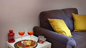 A living room with a sofa, a small table with snacks, two glasses of red wine, and a red lantern.