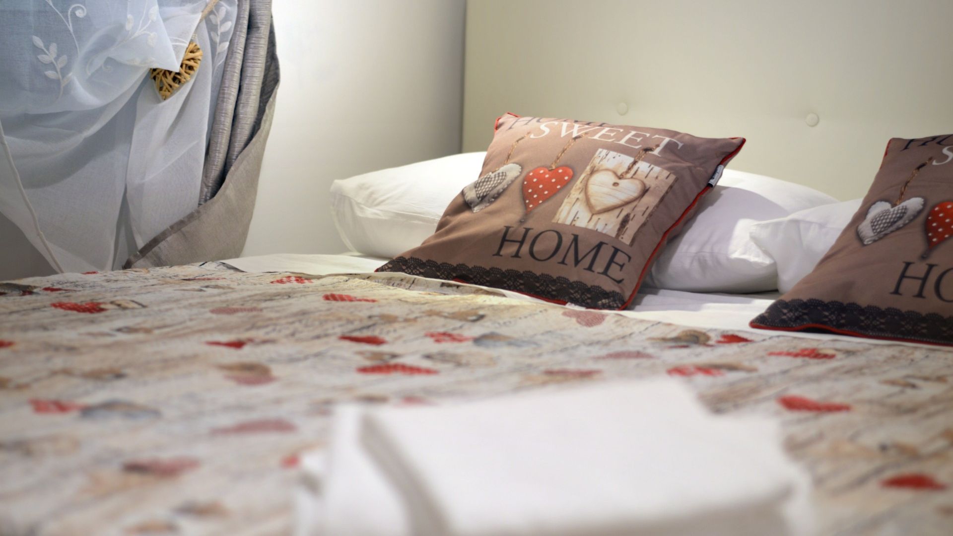 Ein Bett mit einem blumigen Überwurf und Kissen, auf denen 'HOME SWEET HOME' steht.