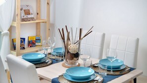 Une table à manger dressée avec des assiettes bleues, des verres transparents et un centre de table composé de branches et d’un vase en verre.