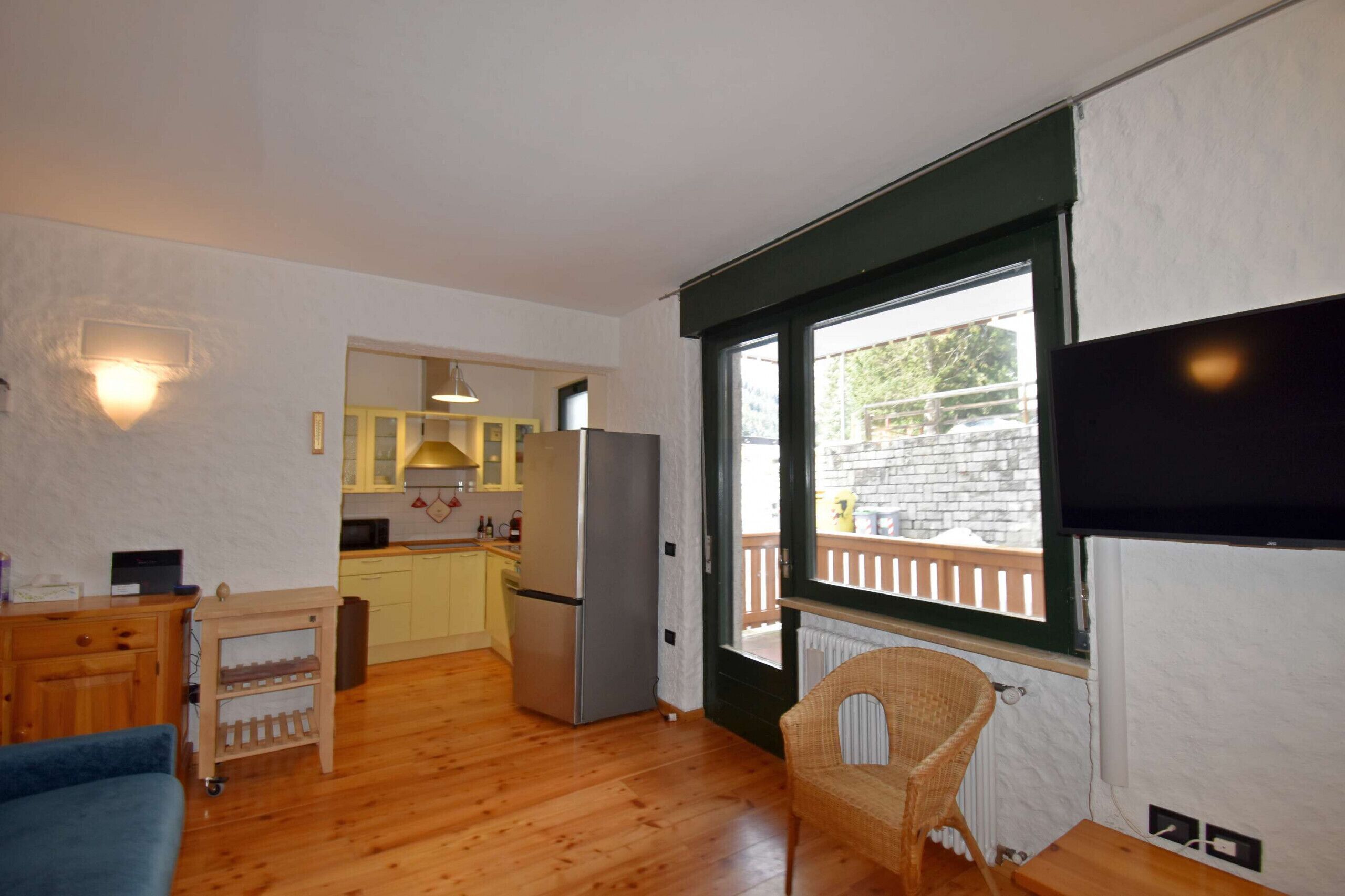 Un espacio habitable compacto con kitchenette, comedor y un ventanal con vistas al exterior.