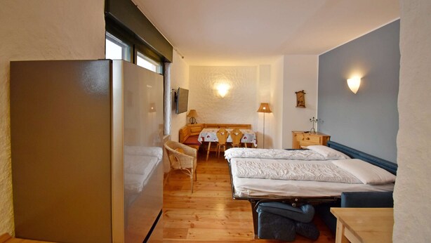 Habitación pequeña con dos camas, una mesa de comedor y un refrigerador.