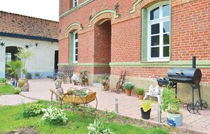 A brick building with a tiled roof, a wheelbarrow, potted plants, a barbecue grill, and a statue. - Awesome home in Fressin with sauna (Fressin)
