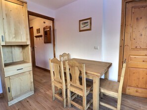 A wooden dining table with chairs, a wooden cabinet, and a door. - Charming 2-Room Apartment with Wi-Fi - Méribel (Méribel)