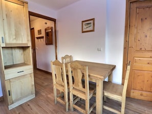 A wooden dining table with chairs, a wooden cabinet, and a door.