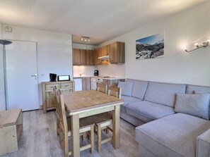 A compact living space with a kitchenette, a dining table with chairs, a sofa, and a wall-mounted picture. - Cozy Apartment in Méribel, 4 pers, Pets allowed (Méribel)
