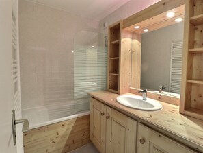 A bathroom with a wooden vanity, a glass shower enclosure, and a large mirror.
