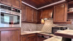 A kitchen with wooden cabinets, a stainless steel oven, a sink, and a microwave.