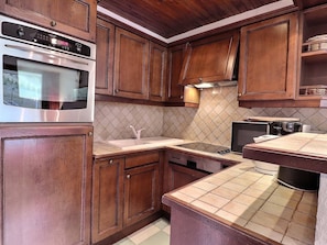 A kitchen with wooden cabinets, a stainless steel oven, a sink, and a microwave. - Comfortable apartment, south balcony, 4 ppl, double bed (Méribel)