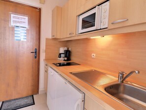 A compact kitchen with a microwave, coffee maker, sink, and dishwasher.
