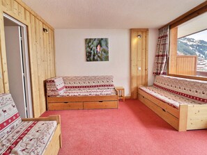 Una habitación acogedora con un banco de madera, una mesita y una ventana con vistas a la montaña.