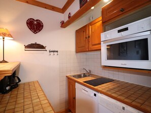 A kitchen with wooden cabinets, a Bosch dishwasher, a white stove, and a heart-shaped decoration on the wall.