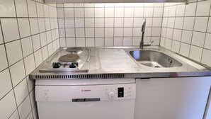 A compact kitchen with a Bosch stove, a sink, and white tiled walls. - Ski-in studio, pets allowed, sleeps 4 (Méribel)