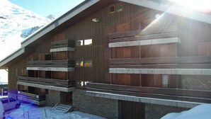 A wooden building with multiple balconies and windows, surrounded by snow.