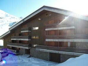 A wooden building with multiple balconies and windows, surrounded by snow.