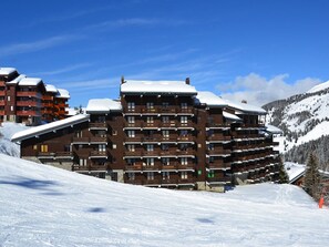 A multi-story hotel with balconies and a ski slope in the background. - Cozy 2-room apt for 4 on the slopes in Méribel (Méribel)