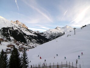 A snow-covered mountain with a ski slope, a ski lift, and a few skiers.