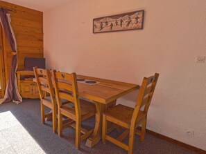 A wooden dining table with chairs, a television on a cabinet, and a wall-mounted picture. - Cozy 2-room apt for 4 on the slopes in Méribel (Méribel)