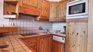 Une cuisine avec des meubles en bois, un four à micro-ondes, un lave-vaisselle et un dosseret carrelé.