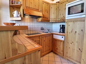 A kitchen with wooden cabinets, a stainless steel sink, a coffee maker, and a microwave.