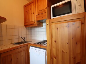 Eine Küche mit Holzausstattung, einer Mikrowelle, einem Geschirrspüler und einer gefliesten Spritzschutzwand.