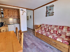 Une cuisine chaleureuse avec des meubles en bois, une table à manger et un canapé recouvert d’un tissu à motifs.
