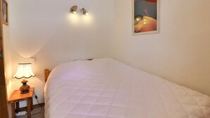 A bedroom with a bed, a bedside lamp, a wall-mounted light fixture, and a framed picture. - 2 Rooms Ideally Located Ski-In Ski-Out - Méribel (Méribel)