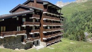 A multi-story wooden chalet with balconies, set against a mountainous backdrop. - 2 Rooms Ideally Located Ski-In Ski-Out - Méribel (Méribel)