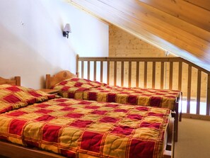Ein Schlafzimmer mit zwei hölzernen Betten, einer geneigten Decke und einem Holzgeländer.