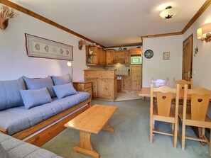 A cozy living room with a sofa, a wooden coffee table, and a dining area with chairs. - Charming 2-Room Apartment Méribel - 5 Pers, South Balcony, Wi-Fi (Méribel)