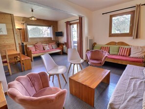 Una habitación acogedora con piso de madera, un sofá, una mesa de madera y una silla.