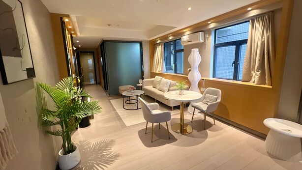 Un salon moderne avec un canapé, deux fauteuils, une table basse et une plante en pot.