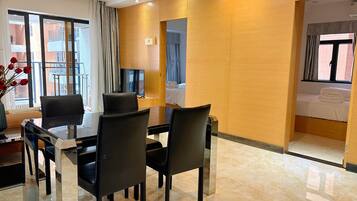 A hotel room with a dining area, a bed, and a TV.