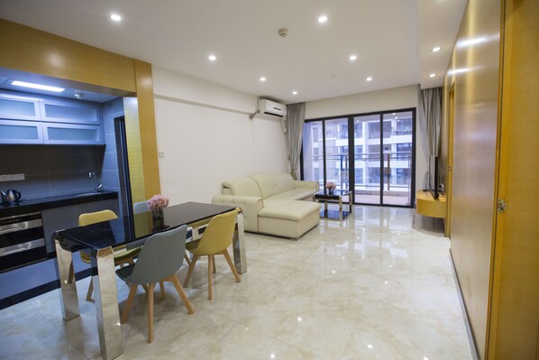 Una sala de estar moderna con un sofá, una mesa de comedor con sillas y una zona de cocina con estufa y fregadero.