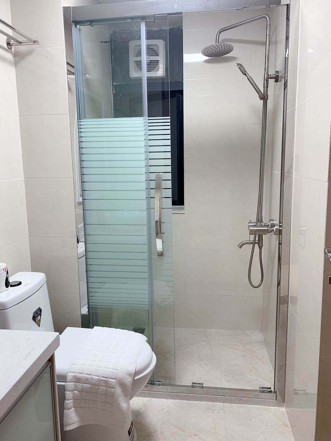 A glass-enclosed shower stall with a handheld showerhead and a handheld shower head.