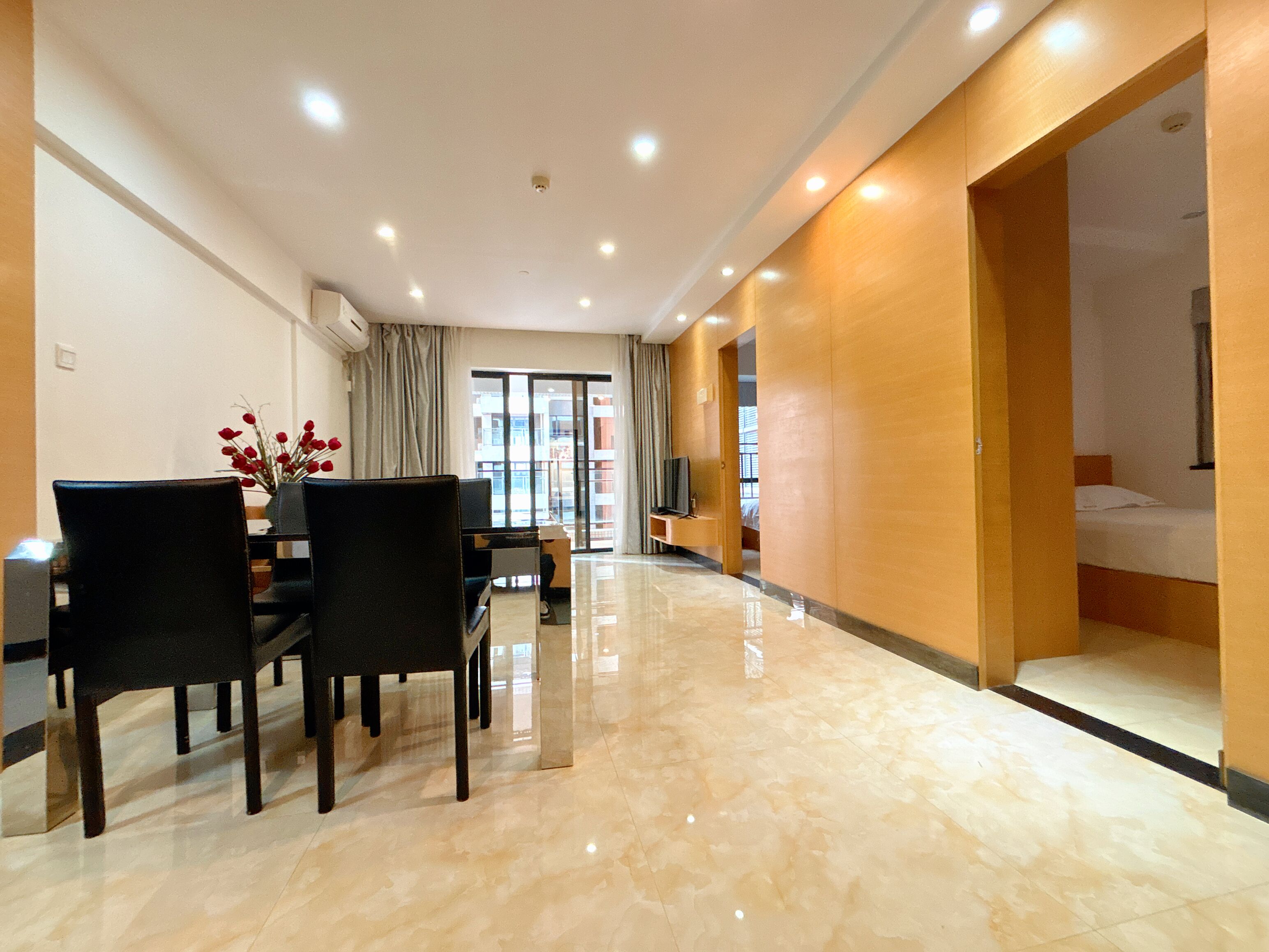 A modern hotel room with a dining area, a TV, and a bed.