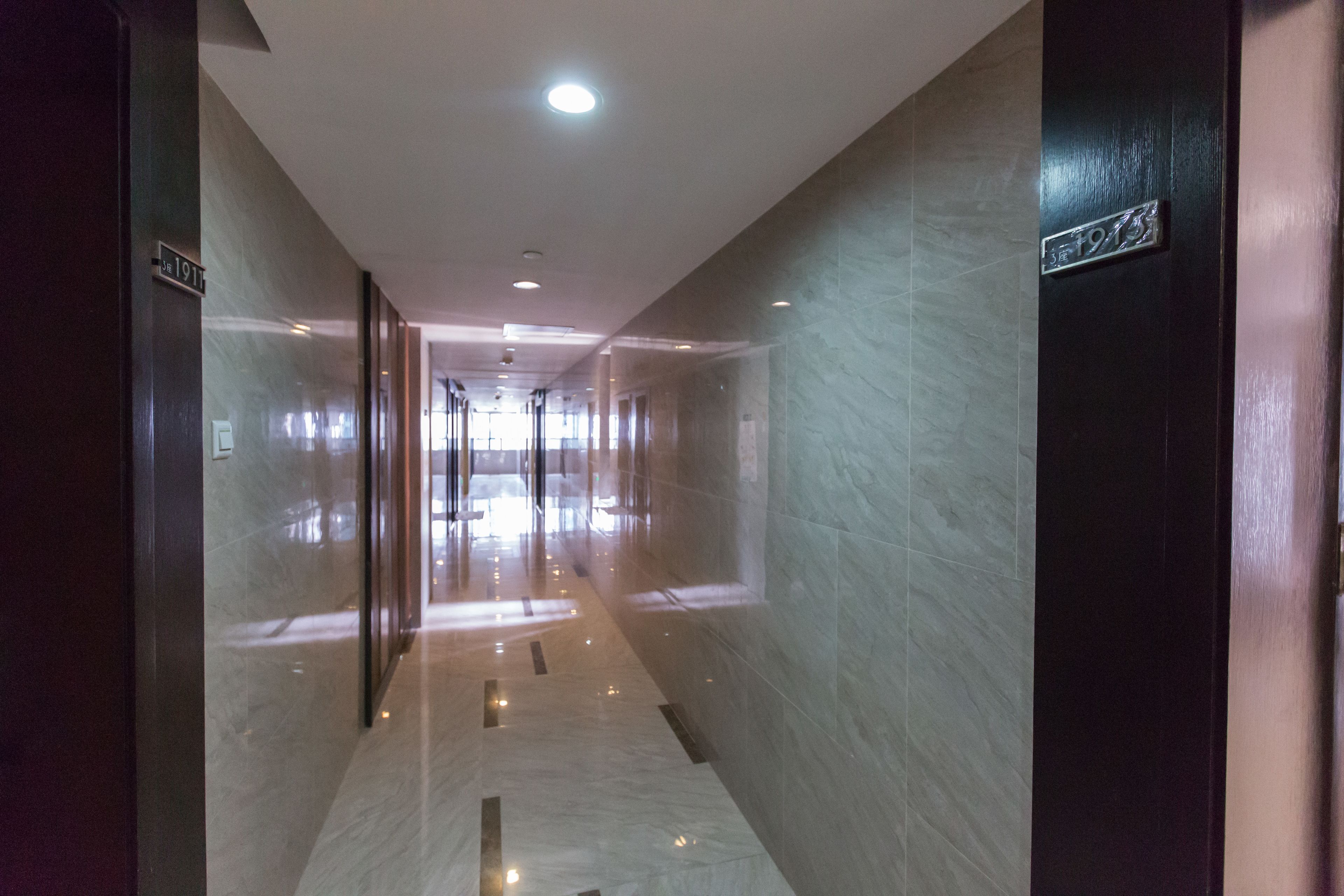 A corridor with marble flooring and walls, featuring a sign with the number 1913.