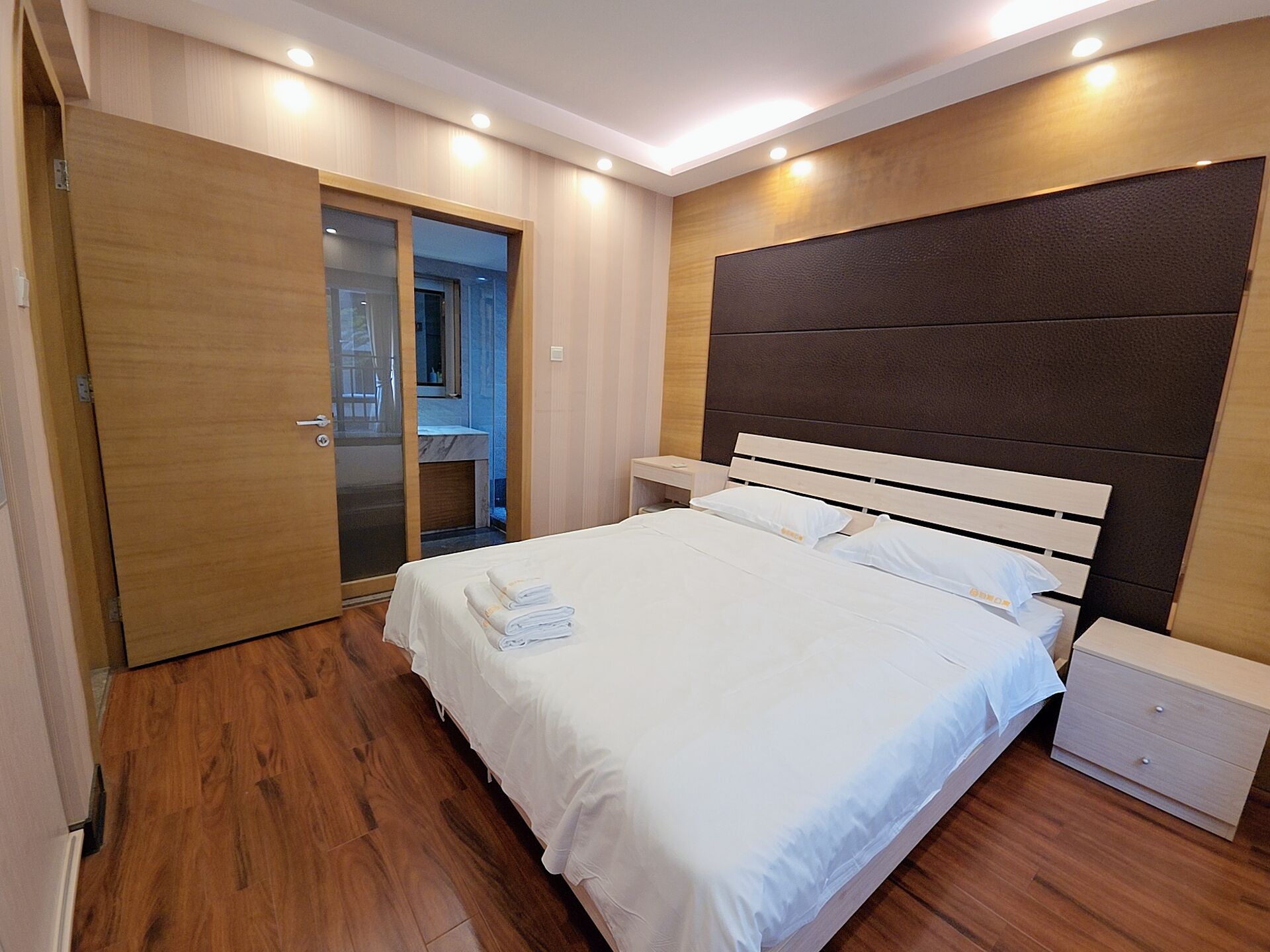 A bedroom with a bed, bedside tables, a wardrobe, and a mirror.