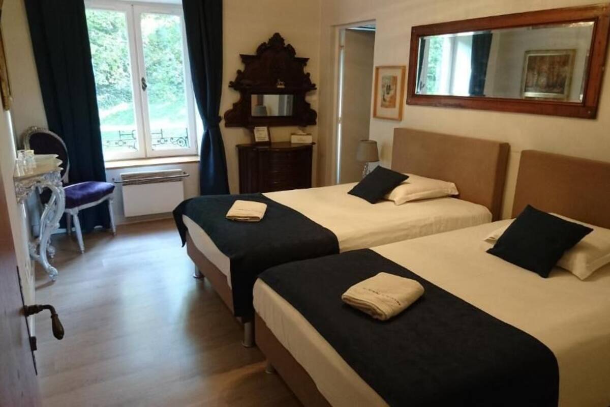 A hotel room with two beds, a dresser, a chair, and a window with curtains.