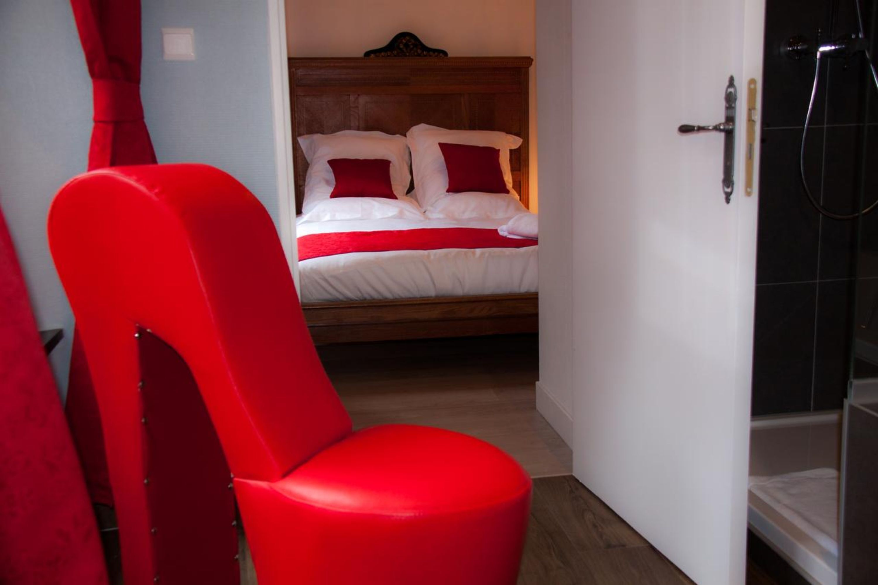Una habitación con una cama, una silla roja y un espacio para ducha.