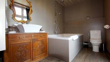 Un baño con tocador de madera, bañera blanca, ducha y retrete.