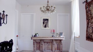 Una habitación con un armario de madera, una araña, una obra de arte enmarcada y un tapiz en la pared.