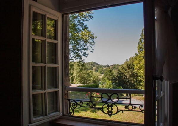 A window with a view of a green landscape, including trees and a road. - Château de l’Aviette (Rancennes)