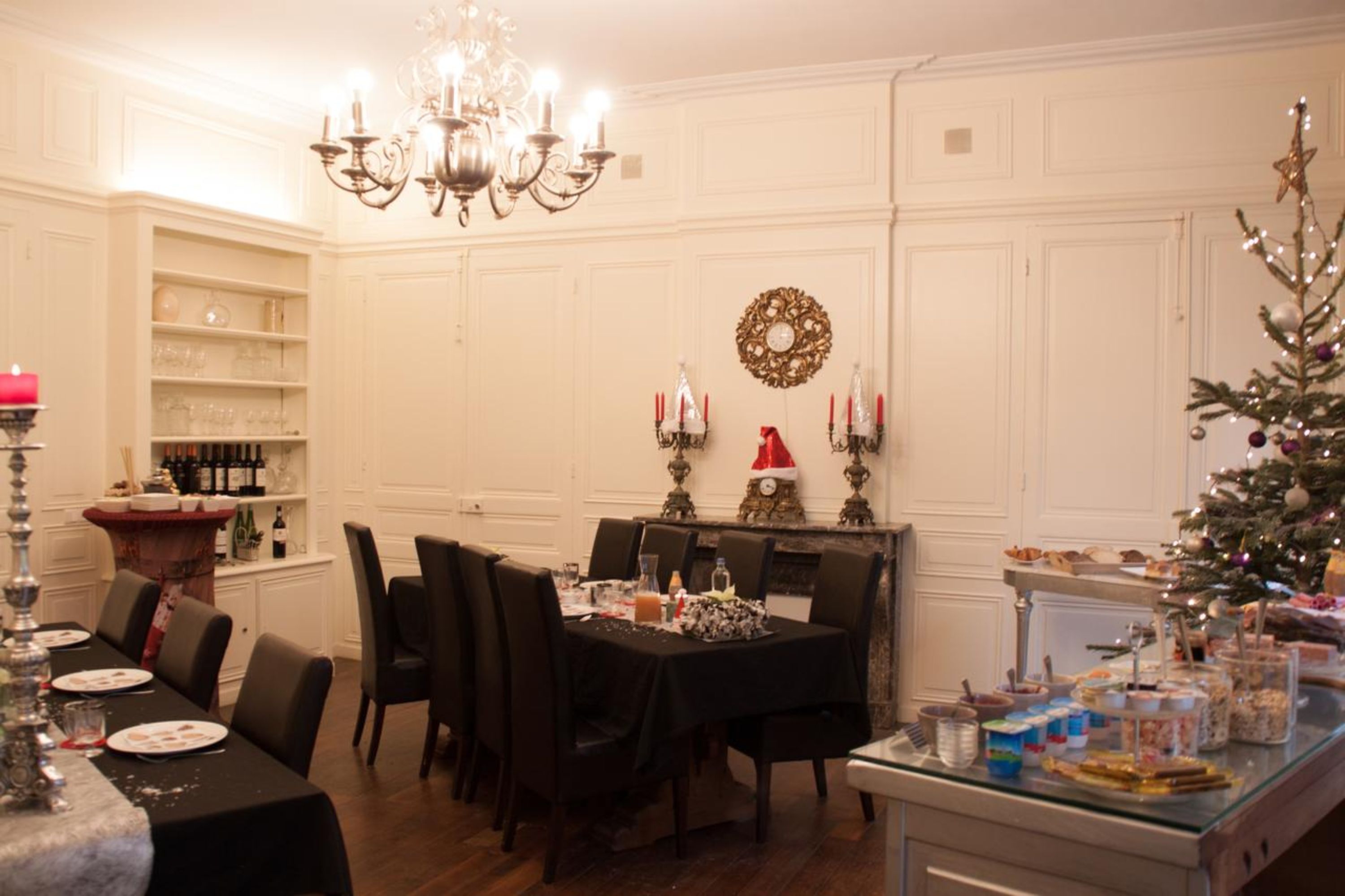 Een eethoek met een kroonluchter, een kerstboom en een buffettafel.