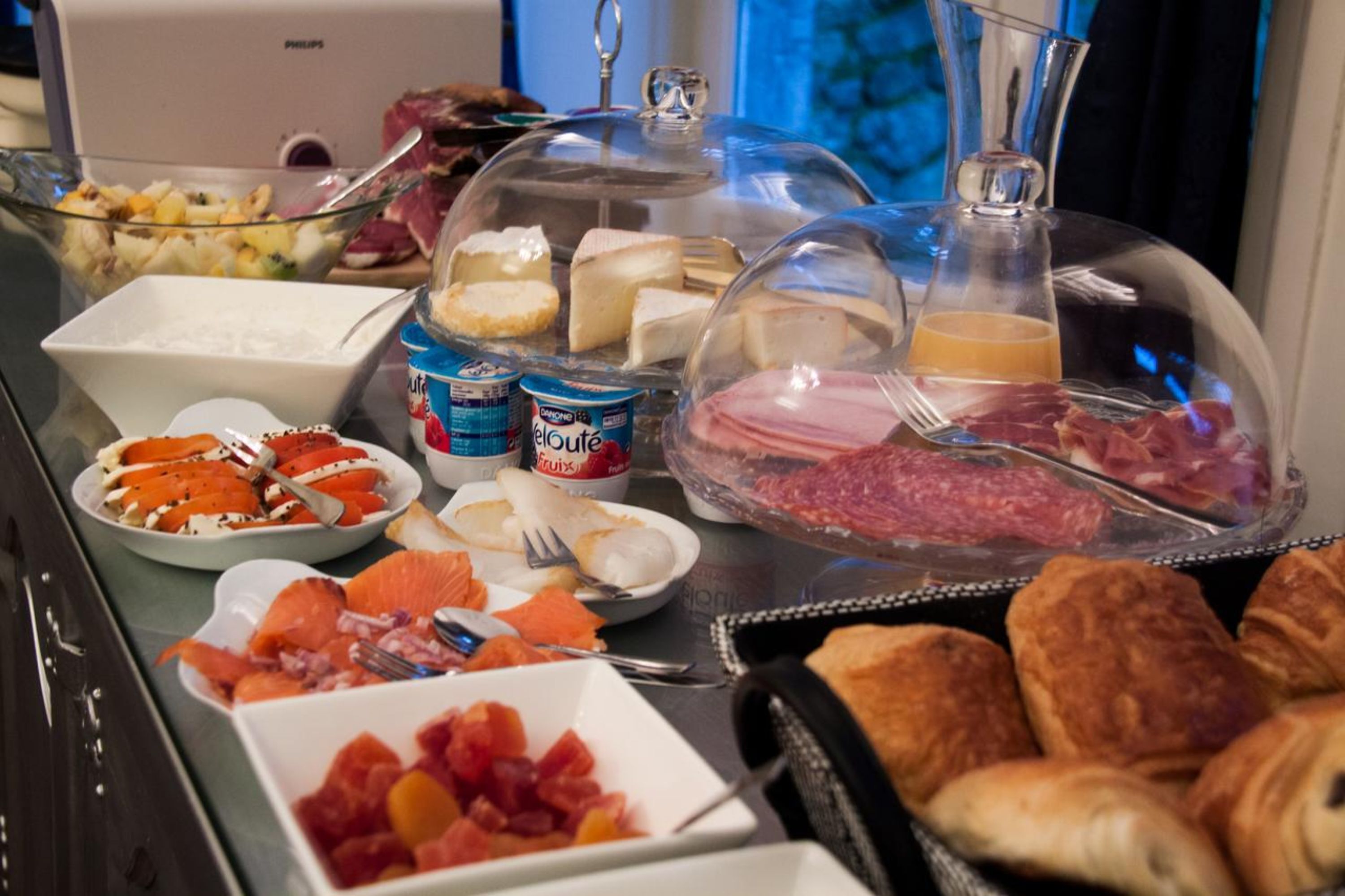 Un buffet de petit-déjeuner proposant une variété d'aliments, notamment des fruits, des fromages, des viandes et des pâtisseries.