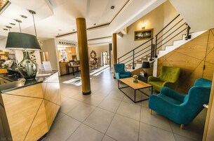Um hall moderno com balcão de atendimento, área de estar e escada.