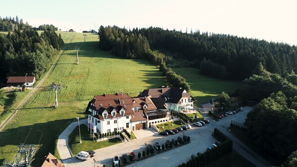 A large, multi-story building with a red-tiled roof, surrounded by a well-maintained lawn and a parking area.